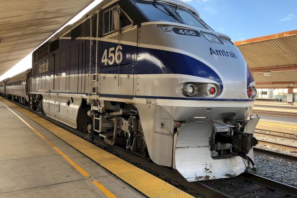 A modern Amtrak train is stationed at a platform with the engine number 456 visible. The train is blue and white.